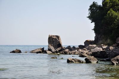 Rock formations in sea against clear sky