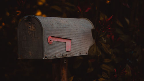 Close-up of mailbox on wood against trees