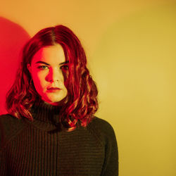 Portrait of beautiful young woman against yellow background