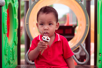 Cute boy holding ice cream cone at playground