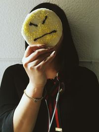 Close-up of woman holding angry face against wall