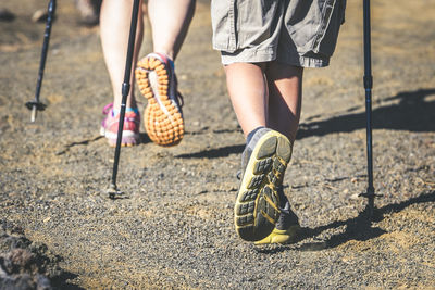 Low section of hikers with hiking poles walking on land