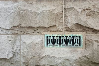 Old turquoise metal grate on stone wall