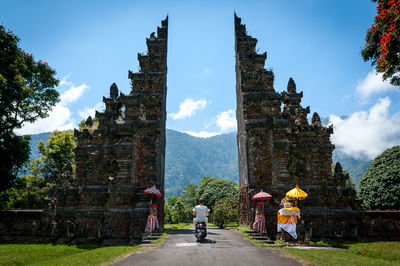 Rear view of men amidst buildings against sky