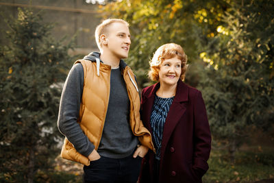 Portrait of smiling couple standing against trees