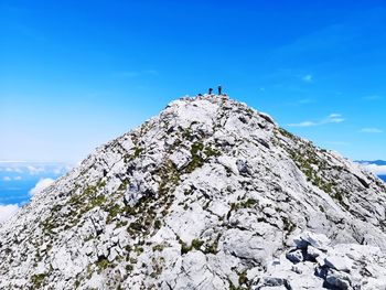 Low angle view of rocks on mountain against blue sky