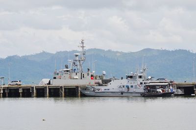 Fishing boats moored at harbor against sky