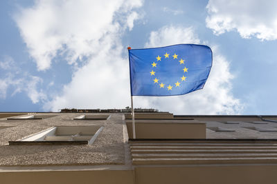 Directly below shot of european union flag on a balcony of a residential building against sky