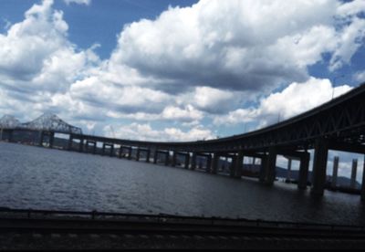 Bridge over river against cloudy sky