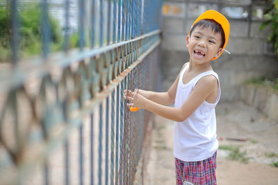 Full length of smiling boy standing against railing