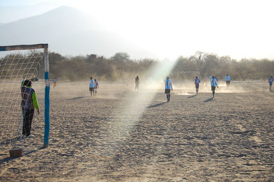 People playing soccer on field during sunny day