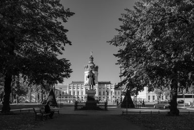 Statue amidst trees and buildings against sky