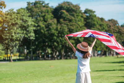 Rear view of woman with umbrella standing on field