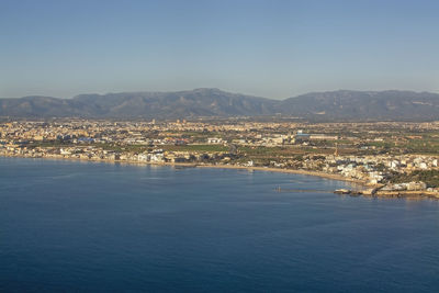 Aerial view of townscape by sea against clear sky