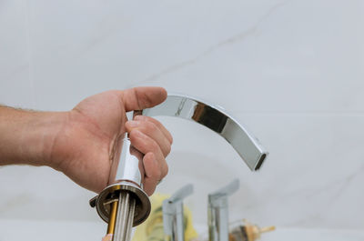 Cropped hand of man repairing faucet at sink