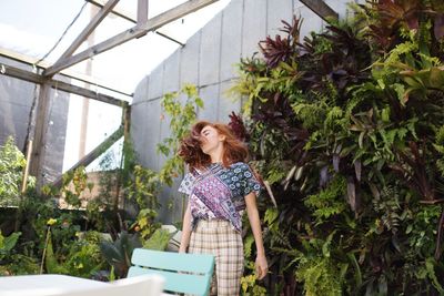 Young woman with tousled hair standing in greenhouse