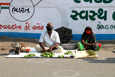 Friends sitting on street at market