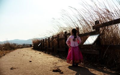 Rear view of woman standing on road against clear sky