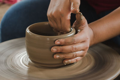 Cropped hand of man molding shape on pottery wheel