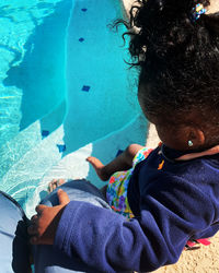 High angle view of girl sitting by swimming pool