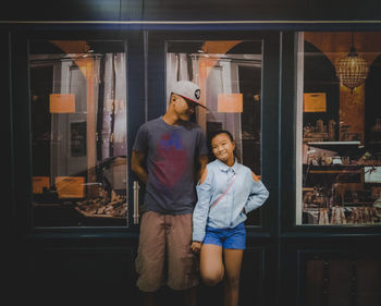Smiling father and daughter standing against store