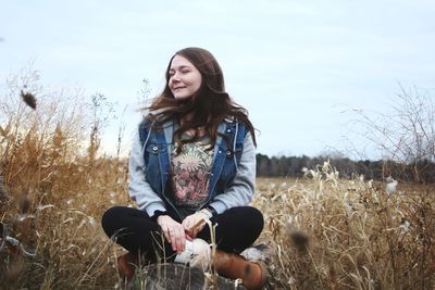 Portrait of smiling young woman sitting on field