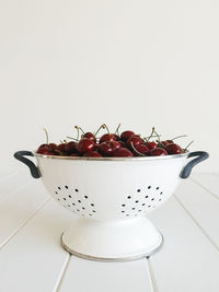 Close-up of fruits in bowl on table against white background