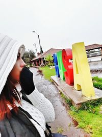 Side view of woman holding umbrella against sky