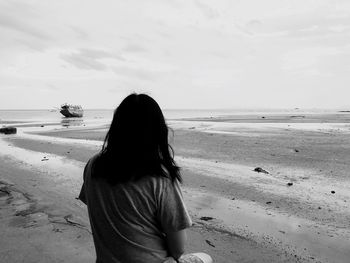 Rear view of woman on beach against sky