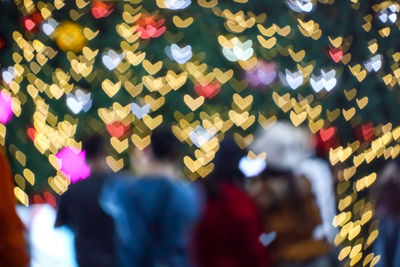 Defocused image of people standing by multi colored lights
