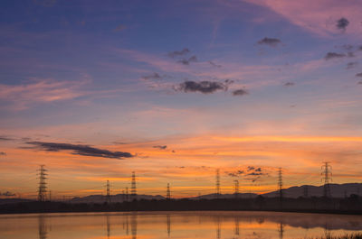 Lined high voltage poles and reflections in the beautiful morning water and lake view, 