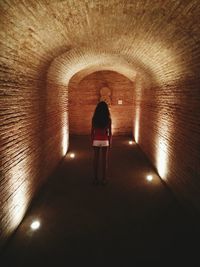 Rear view of woman standing in tunnel