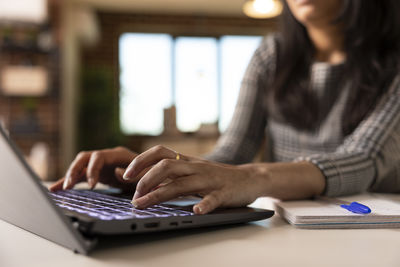 Midsection of woman using laptop on table