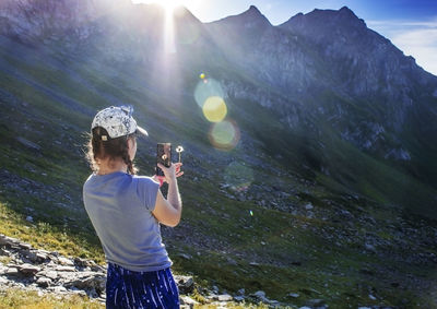 Young woman photographing dandelion in mountains