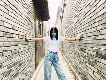 Portrait of teenage girl standing against wall