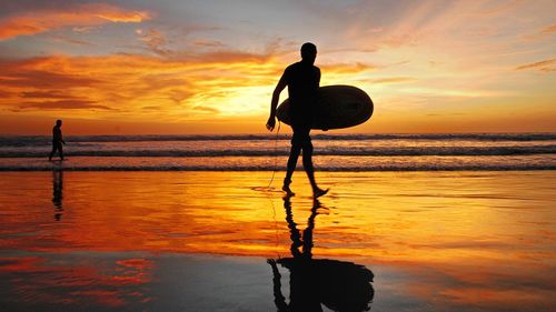 Silhouette of people on beach at sunset