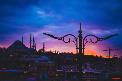 Silhouette of buildings against cloudy sky at dusk