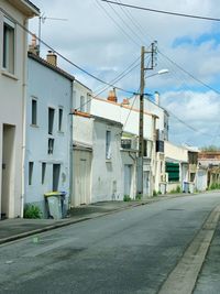 Street amidst houses against sky in city