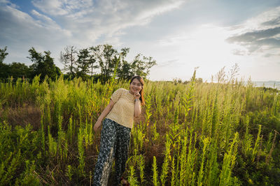 Portrait of smiling woman standing on land against sky