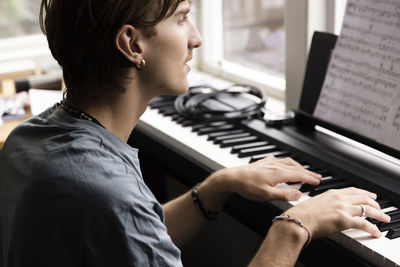Concentrated young man practicing piano at home