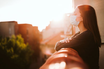 Woman wearing mask while standing in balcony