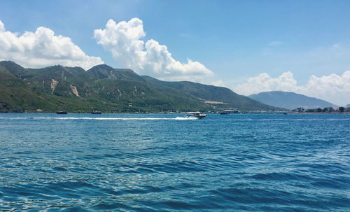 Scenic view of sea by mountains against sky