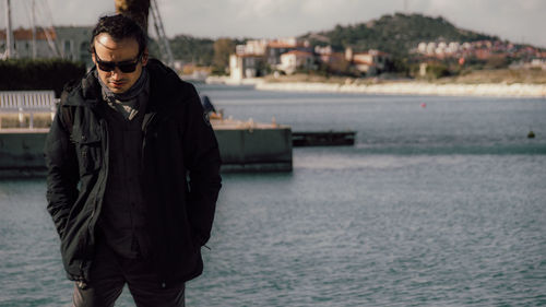 Young man wearing sunglasses standing at sea shore