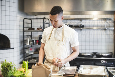 Confident male chef preparing food at kitchen counter in restaurant