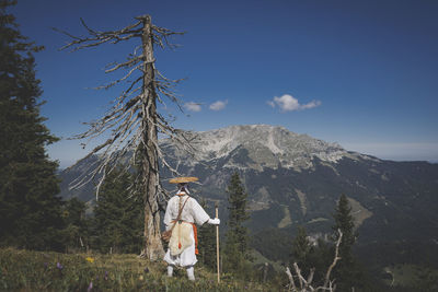 Rear view of man walking on mountain road against sky