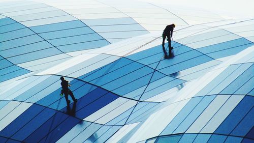 Low angle view of people walking on modern glass building