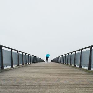 Rear view of woman walking on footbridge