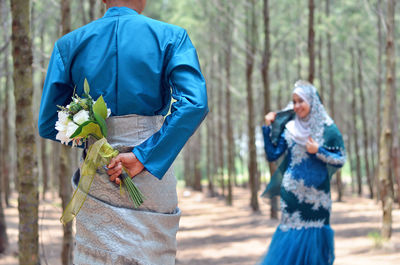 Rear view of people holding flower in forest