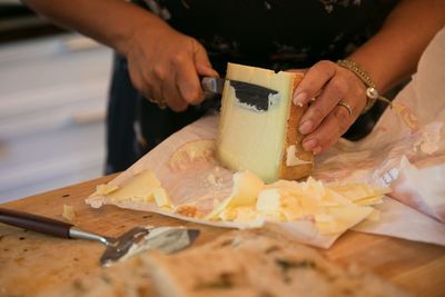 Midsection of woman slicing cheese