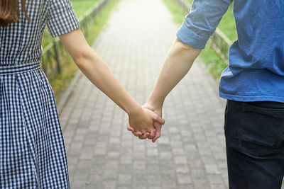 Midsection of couple holding hands